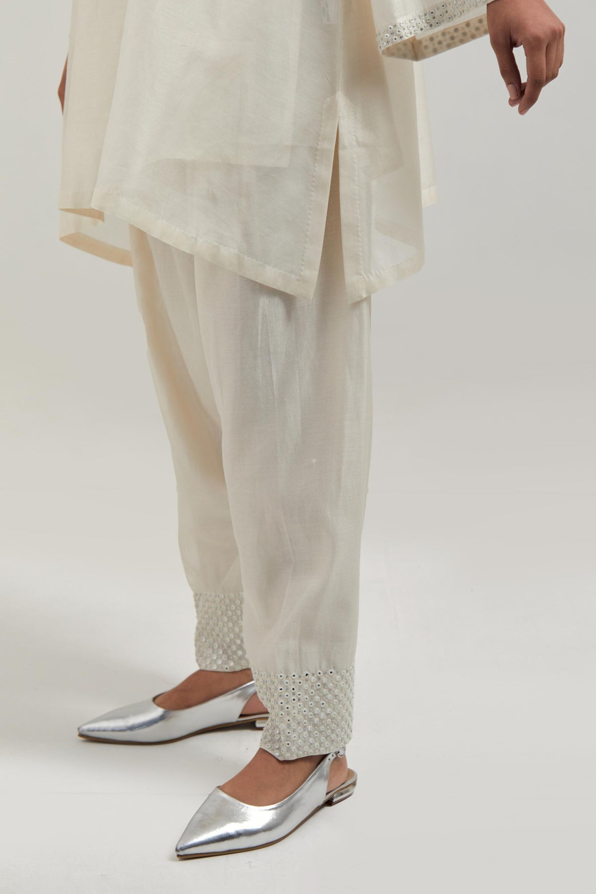 Off white silk Chanderi short A-line kurta set with hand-embroidered mirror work at the neck and bell sleeves.