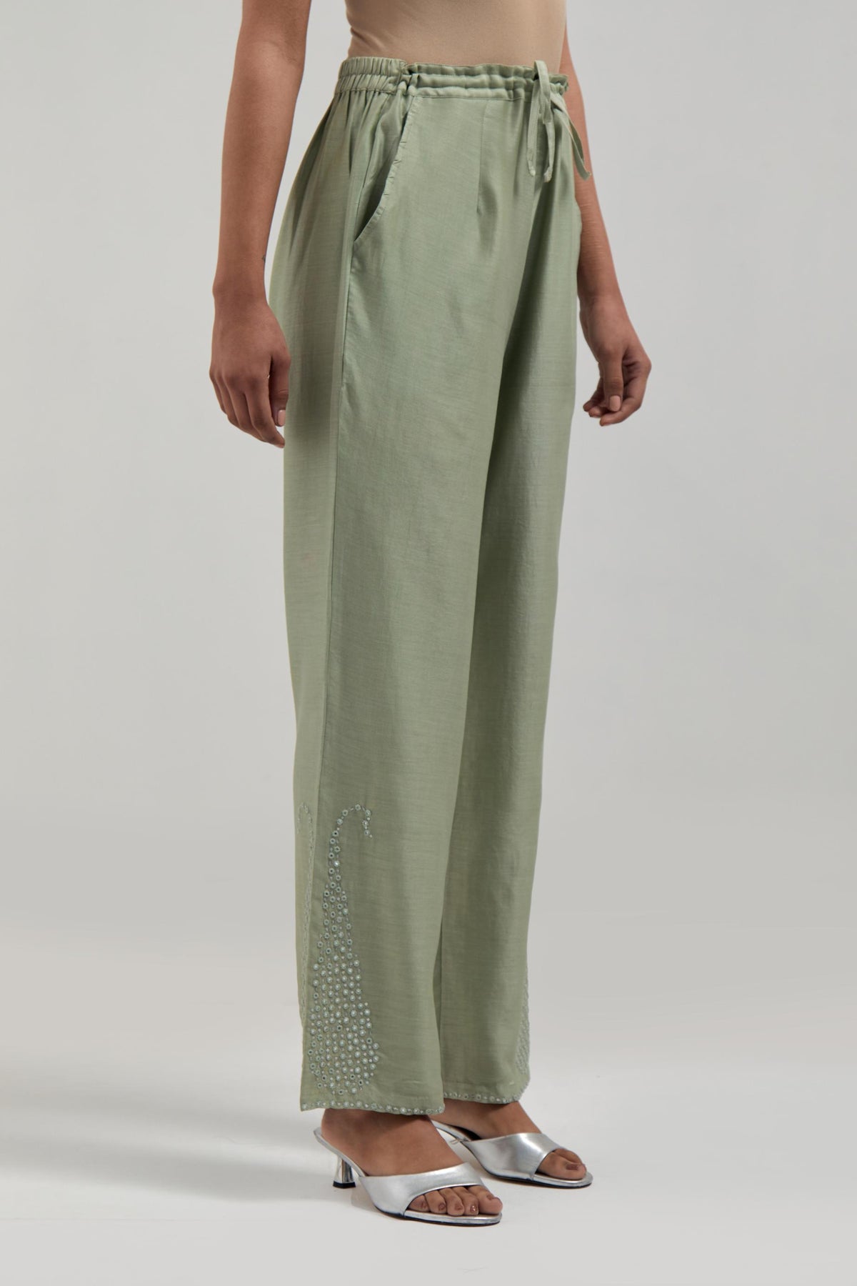 Green silk Chanderi pants with hand-embroidered paisley motifs with delicate mirror and sequins work at the hem.