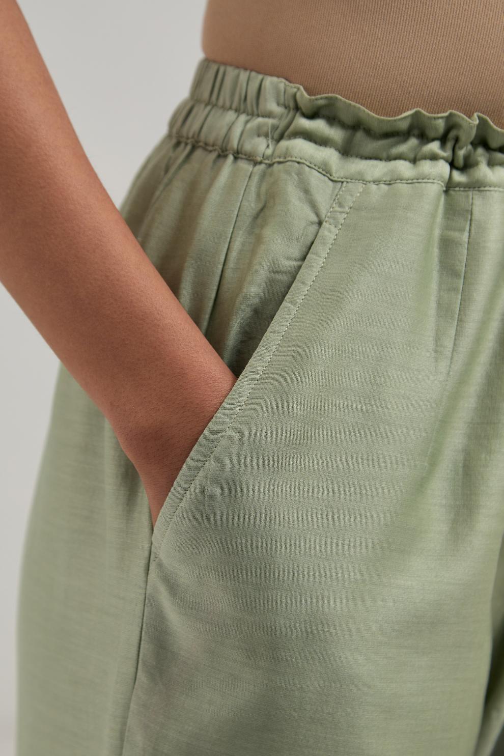 Green silk Chanderi straight pants with narrow organza scalloped hem and hand-embroidered diamond motifs with delicate mirror & sequins work at the sides.