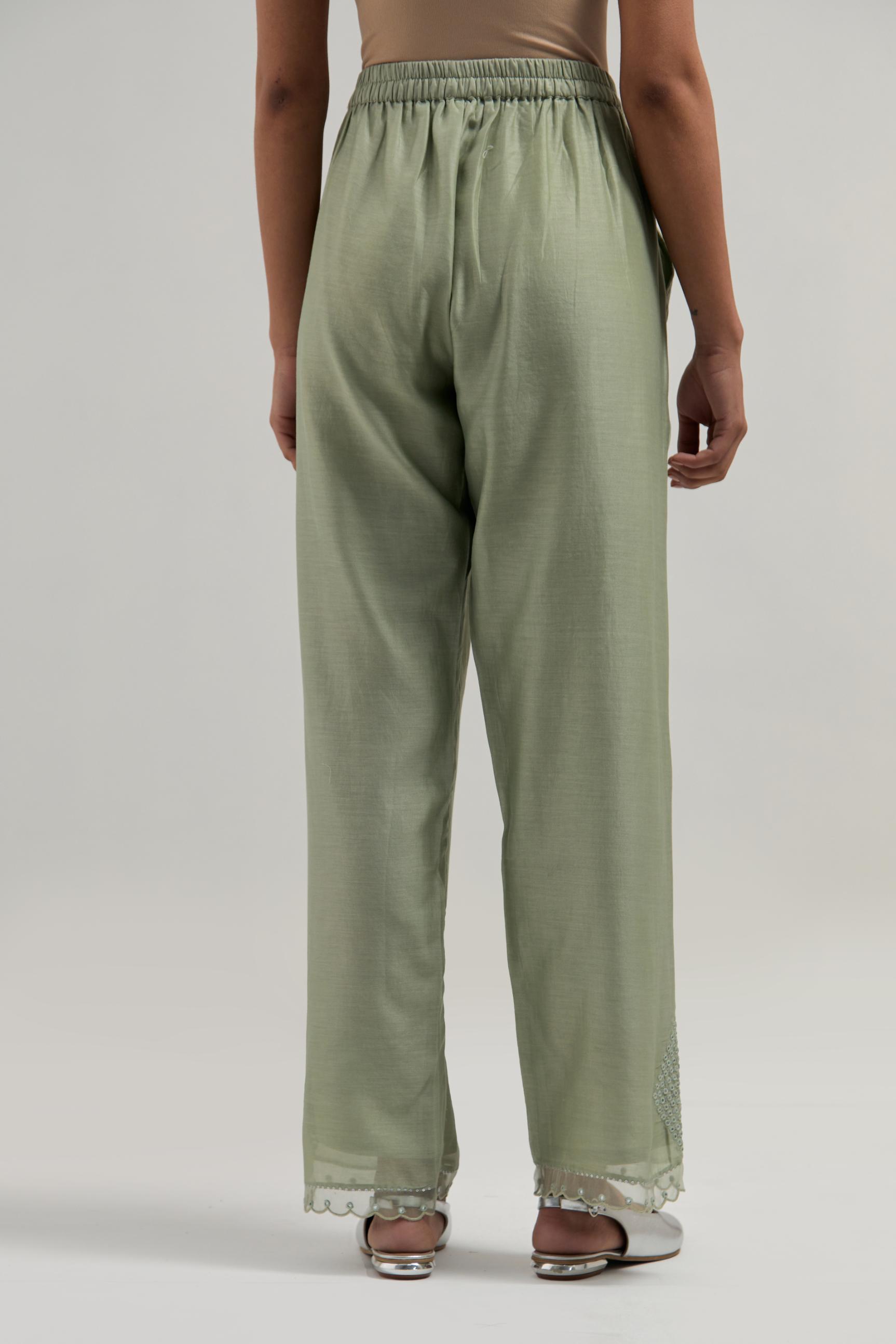Green silk Chanderi straight pants with narrow organza scalloped hem and hand-embroidered diamond motifs with delicate mirror & sequins work at the sides.