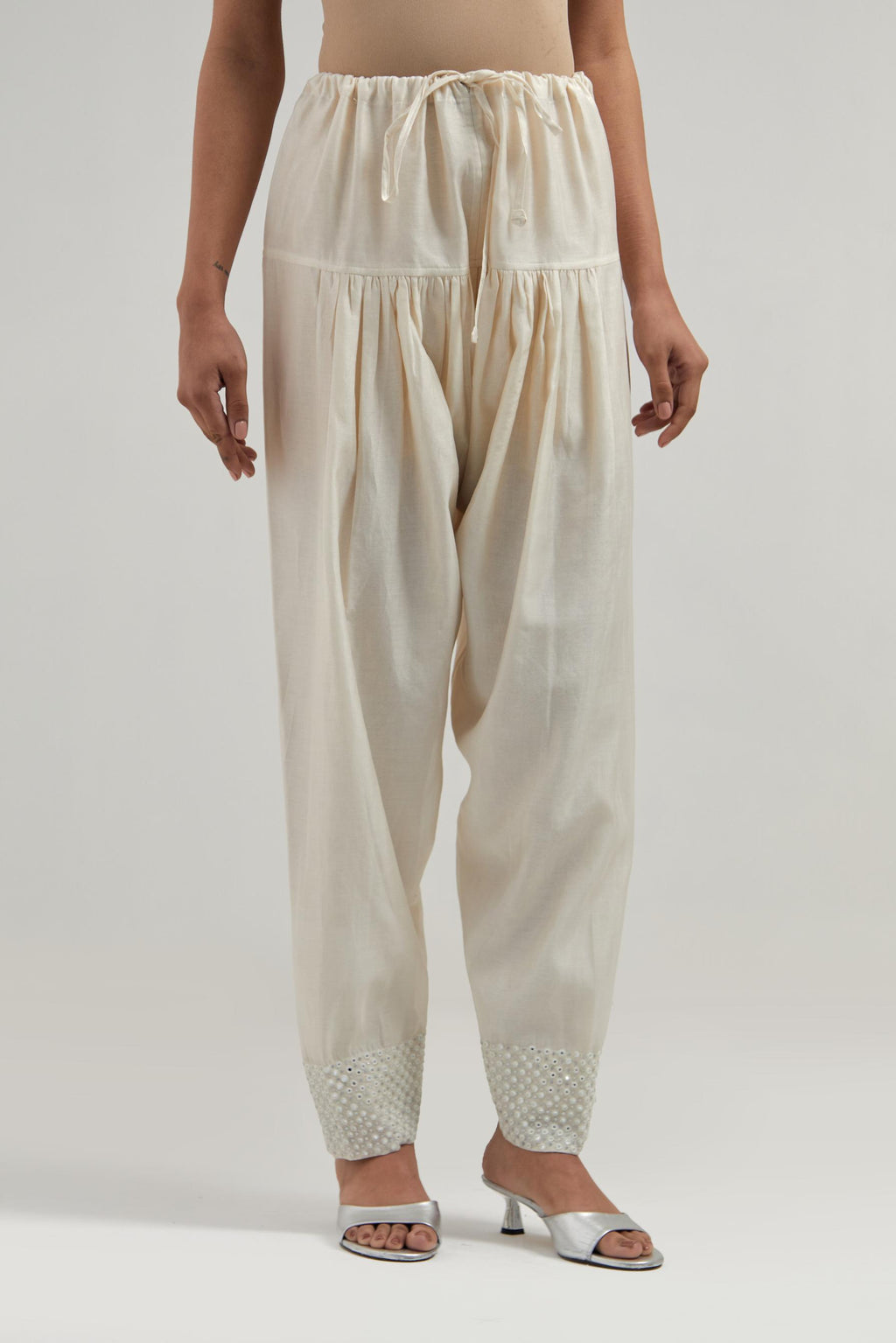 Off white silk Chanderi salwar with hand-embroidered mirror & sequins work in a broad border at the hem.