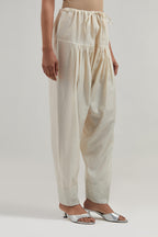 Off white silk Chanderi salwar with hand-embroidered mirror & sequins work in a broad border at the hem.
