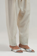Off white silk Chanderi salwar with hand-embroidered mirror & sequins work in a broad border at the hem.