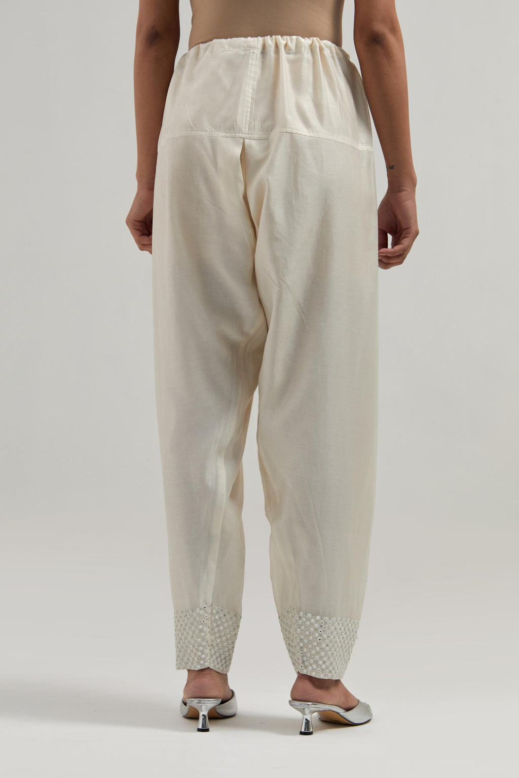 Off white silk Chanderi salwar with hand-embroidered mirror & sequins work in a broad border at the hem.
