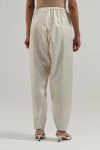 Off white silk Chanderi salwar with hand-embroidered mirror & sequins work in a broad border at the hem.