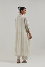 Off white silk Chanderi long kaftan with hand-embroidered mirror and sequins at the neck and diamond motifs along the sides, paired with Off white silk Chanderi straight pants with narrow organza scalloped hem and hand-embroidered diamond motifs.