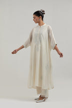 Off white silk Chanderi long kaftan with hand-embroidered mirror and sequins at the neck and diamond motifs along the sides, paired with Off white silk Chanderi straight pants with narrow organza scalloped hem and hand-embroidered diamond motifs.