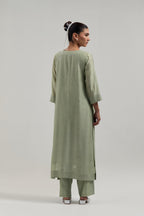 Green silk Chanderi straight kurta set with hand-embroidered mirror at the neck, hem and sleeves, highlighted with scattered silver sequin and mirror embellishments all-over.