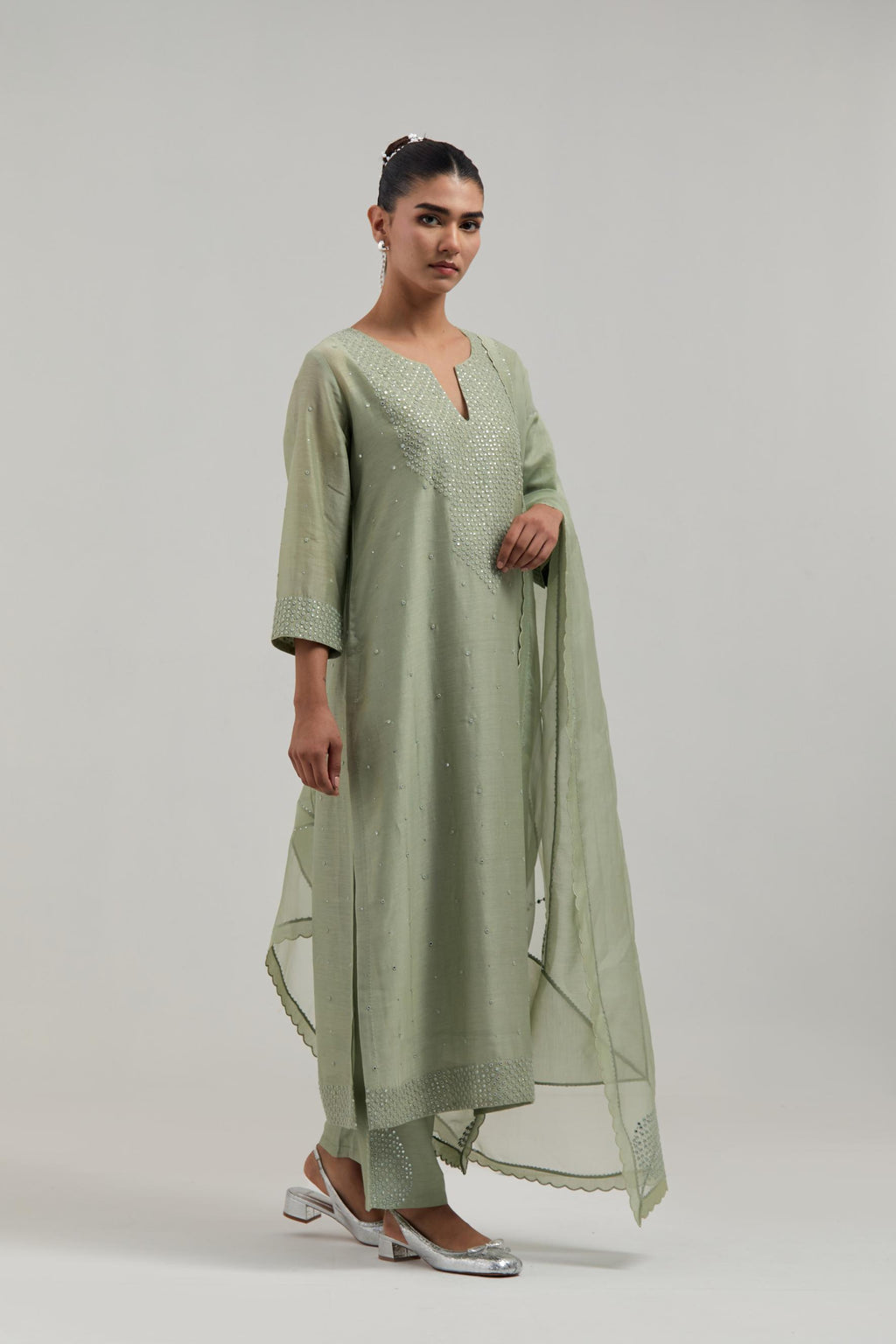 Green silk Chanderi straight kurta set with hand-embroidered mirror at the neck, hem and sleeves, highlighted with scattered silver sequin and mirror embellishments all-over.