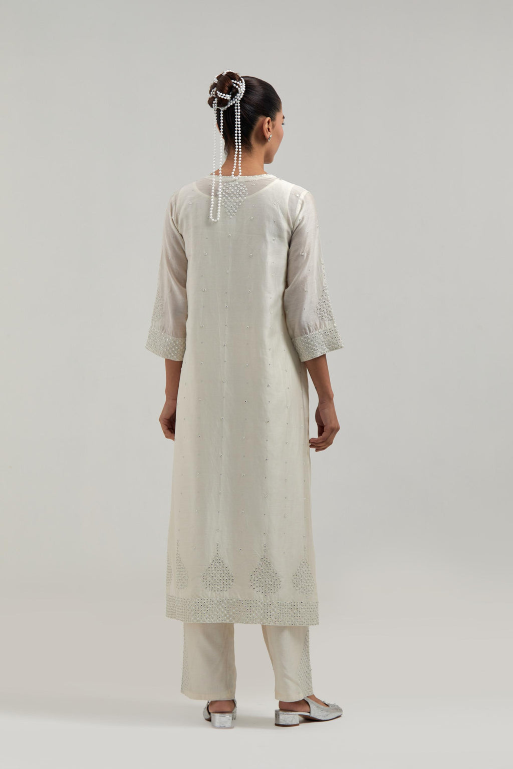 Off white silk Chanderi straight kurta set with hand-embroidered mirror at the neck, borders running along the hem and sleeve edges, and scattered silver sequin and mirror embellishments all-over.