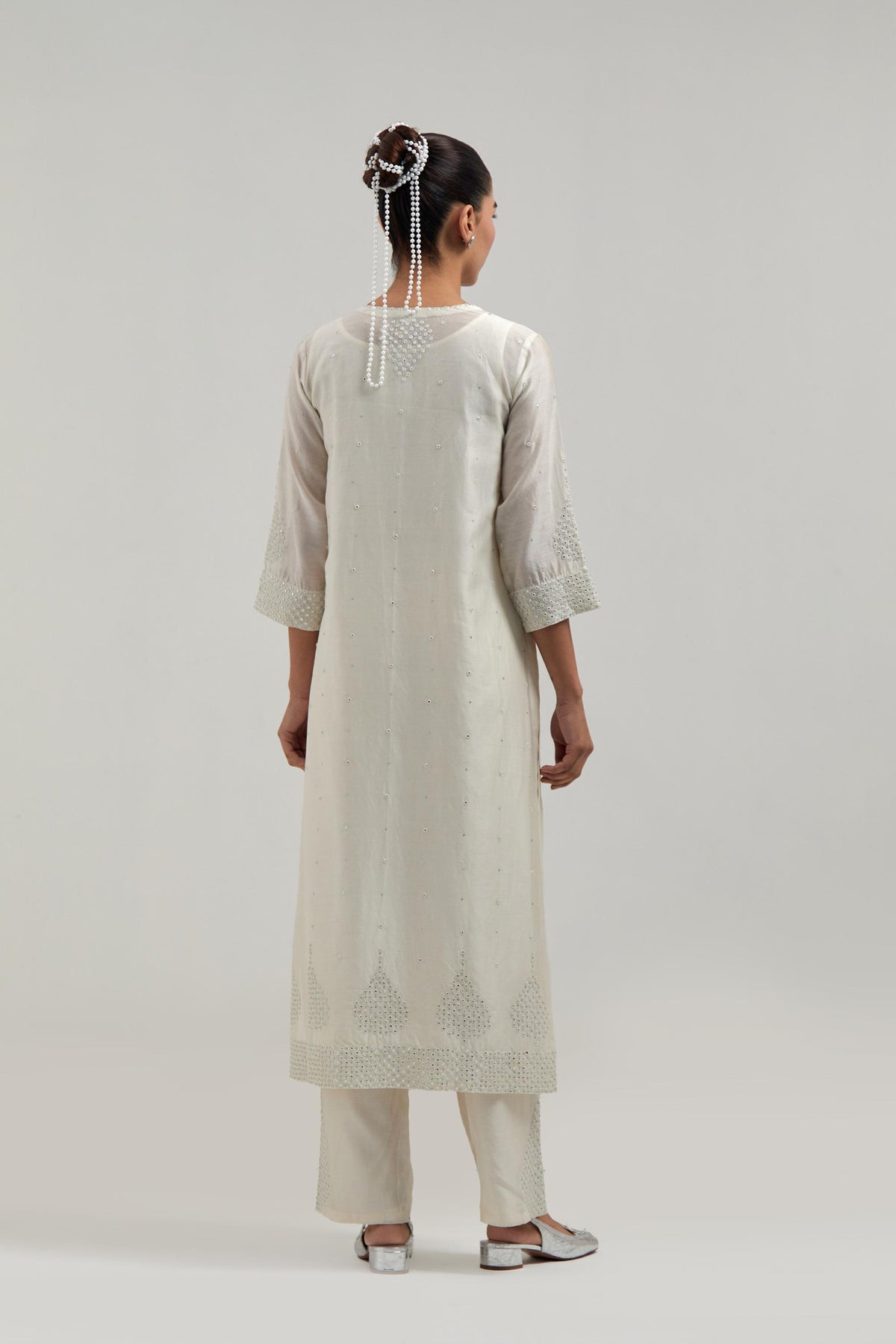 Off white silk Chanderi straight kurta set with hand-embroidered mirror at the neck, borders running along the hem and sleeve edges, and scattered silver sequin and mirror embellishments all-over.