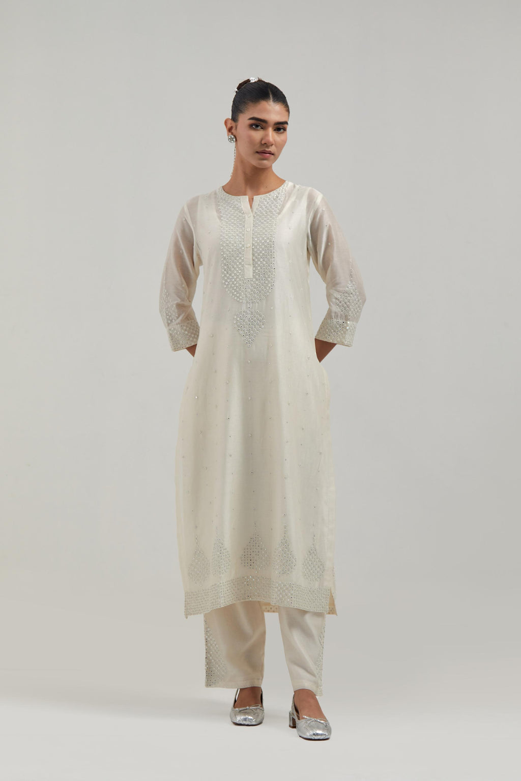 Off white silk Chanderi straight kurta set with hand-embroidered mirror at the neck, borders running along the hem and sleeve edges, and scattered silver sequin and mirror embellishments all-over.