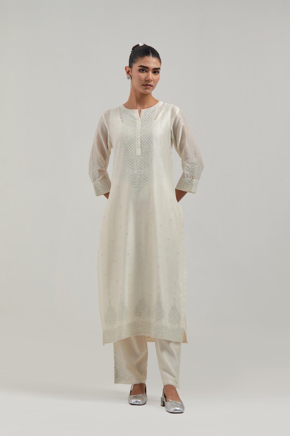 Off white silk Chanderi straight kurta set with hand-embroidered mirror at the neck, borders running along the hem and sleeve edges, and scattered silver sequin and mirror embellishments all-over.