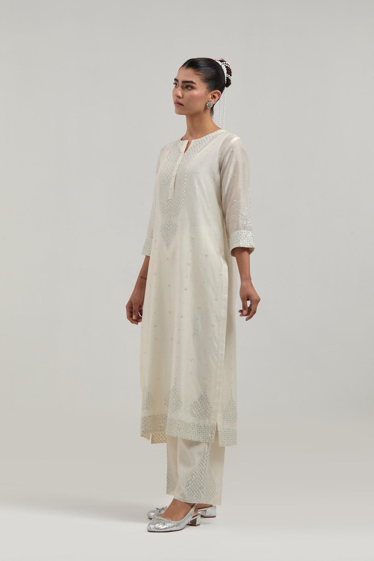Off white silk Chanderi straight kurta set with hand-embroidered mirror at the neck, borders running along the hem and sleeve edges, and scattered silver sequin and mirror embellishments all-over.