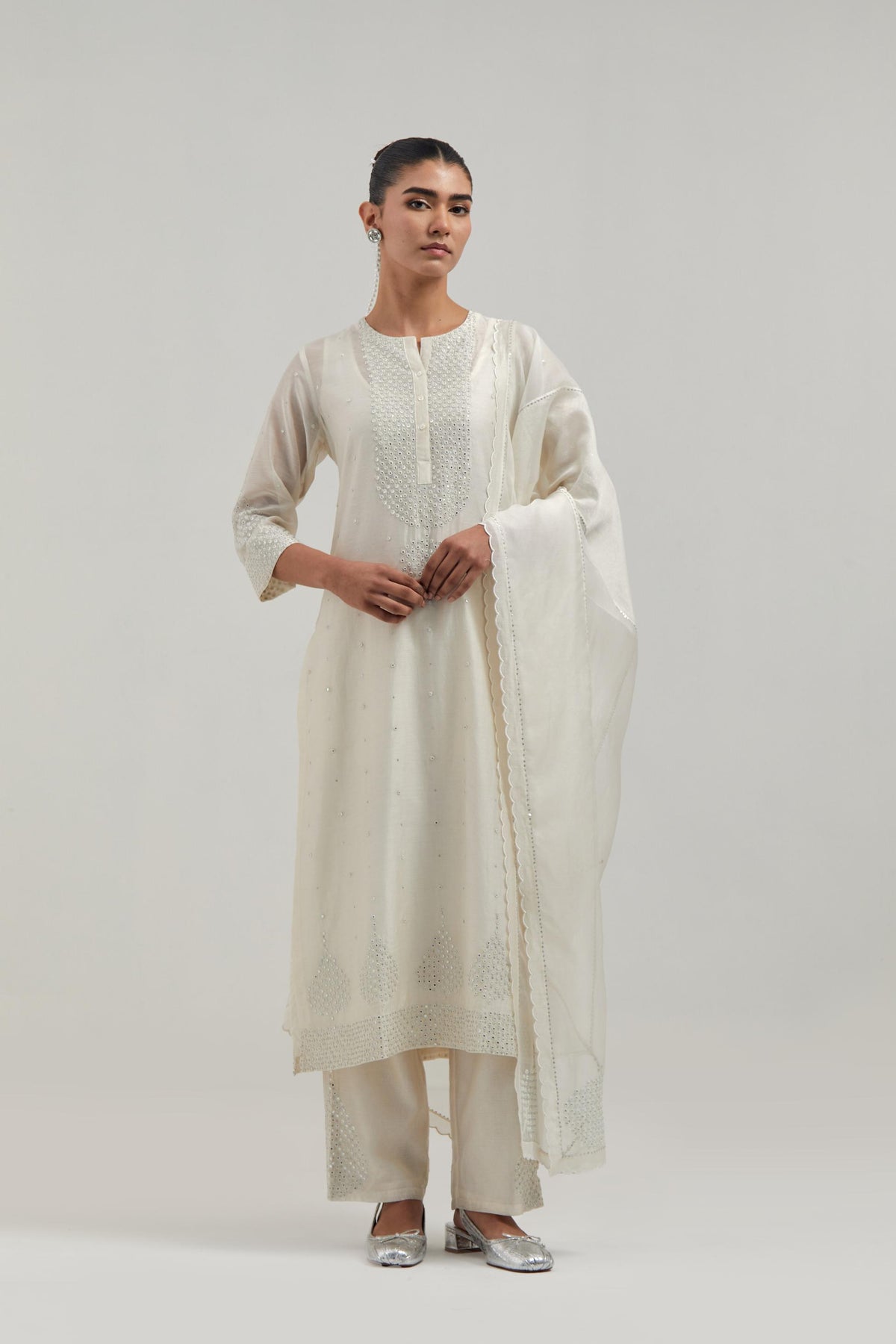 Off white silk Chanderi straight kurta set with hand-embroidered mirror at the neck, borders running along the hem and sleeve edges, and scattered silver sequin and mirror embellishments all-over.