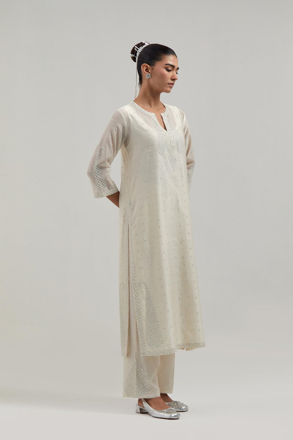 Off white silk Chanderi straight kurta set with hand-embroidered paisley motifs with delicate mirror and sequins work at neck, hem, and sleeves, with narrow borders along the edges.