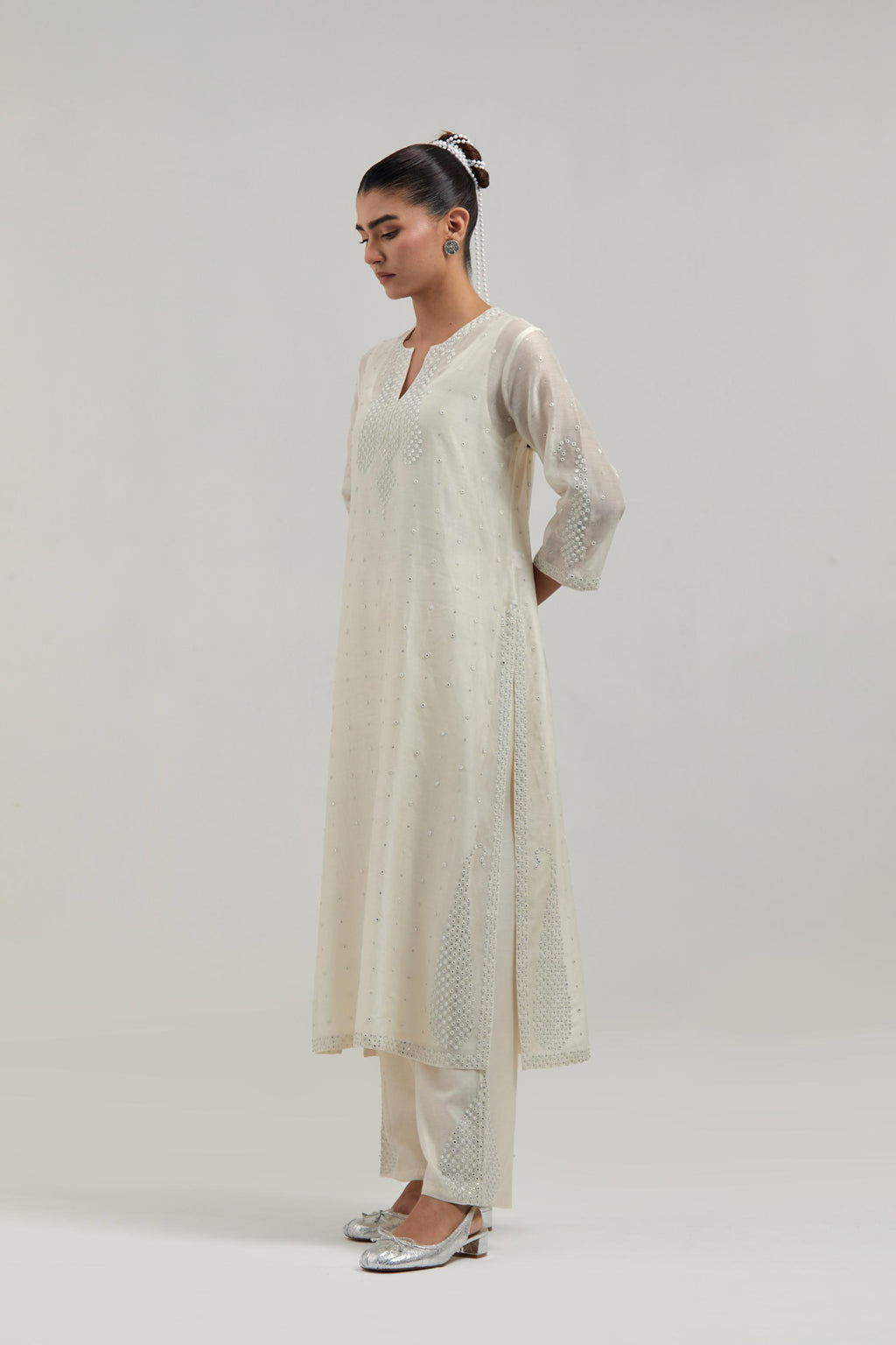 Off white silk Chanderi straight kurta set with hand-embroidered paisley motifs with delicate mirror and sequins work at neck, hem, and sleeves, with narrow borders along the edges.