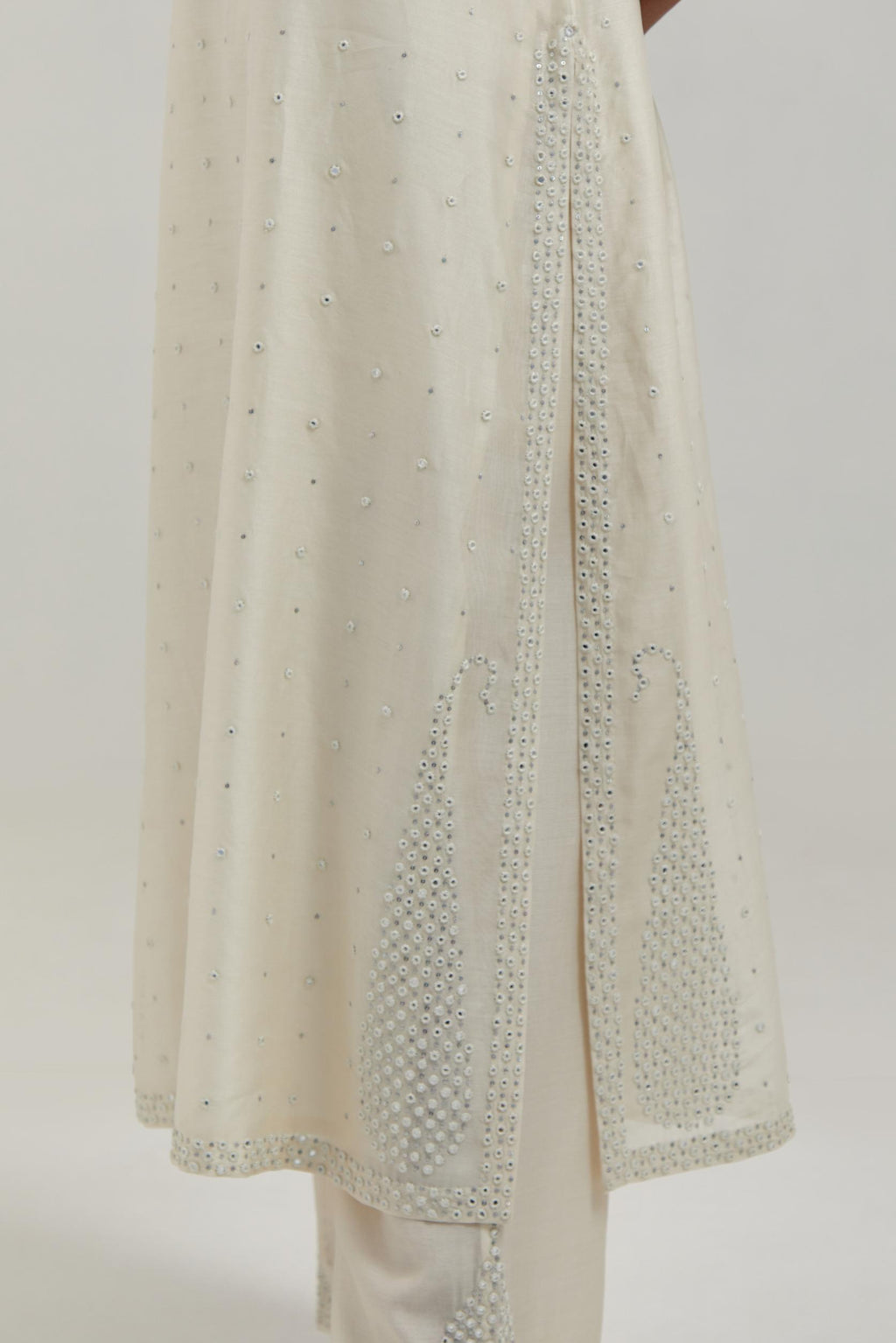 Off white silk Chanderi straight kurta set with hand-embroidered paisley motifs with delicate mirror and sequins work at neck, hem, and sleeves, with narrow borders along the edges.