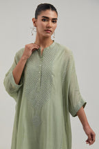 Green silk Chanderi long kaftan with hand-embroidered mirror and sequins at the neck and diamond motifs along the sides, paired with Green silk Chanderi straight pants with narrow organza scalloped hem and hand-embroidered diamond motifs with delicate.