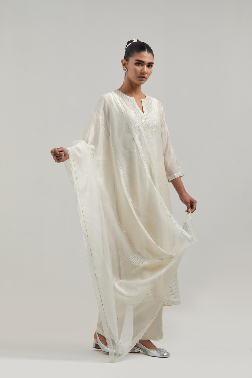 Off white silk Chanderi straight kurta set with hand-embroidered paisley motifs with delicate mirror and sequins work at neck, hem, and sleeves, with narrow borders along the edges.