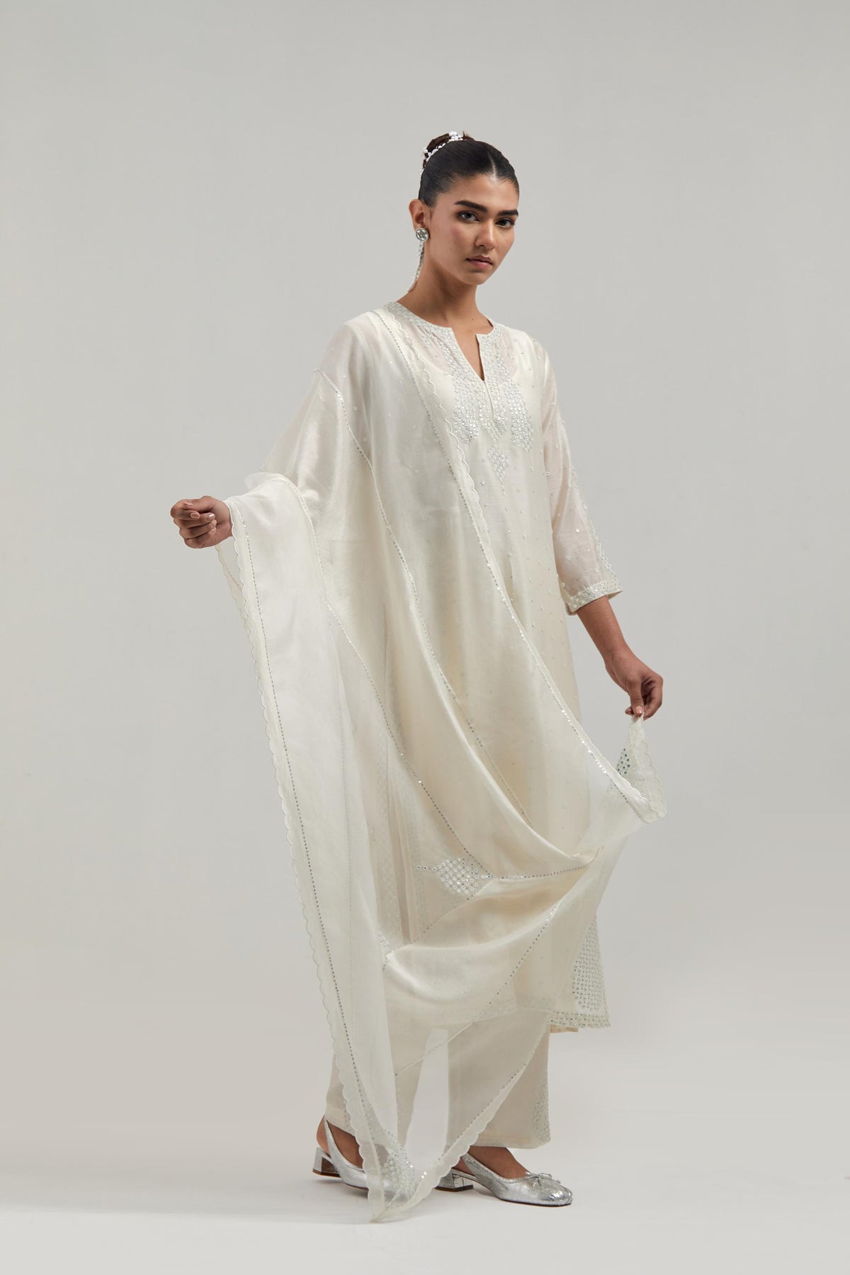 Off white silk Chanderi straight kurta set with hand-embroidered paisley motifs with delicate mirror and sequins work at neck, hem, and sleeves, with narrow borders along the edges.