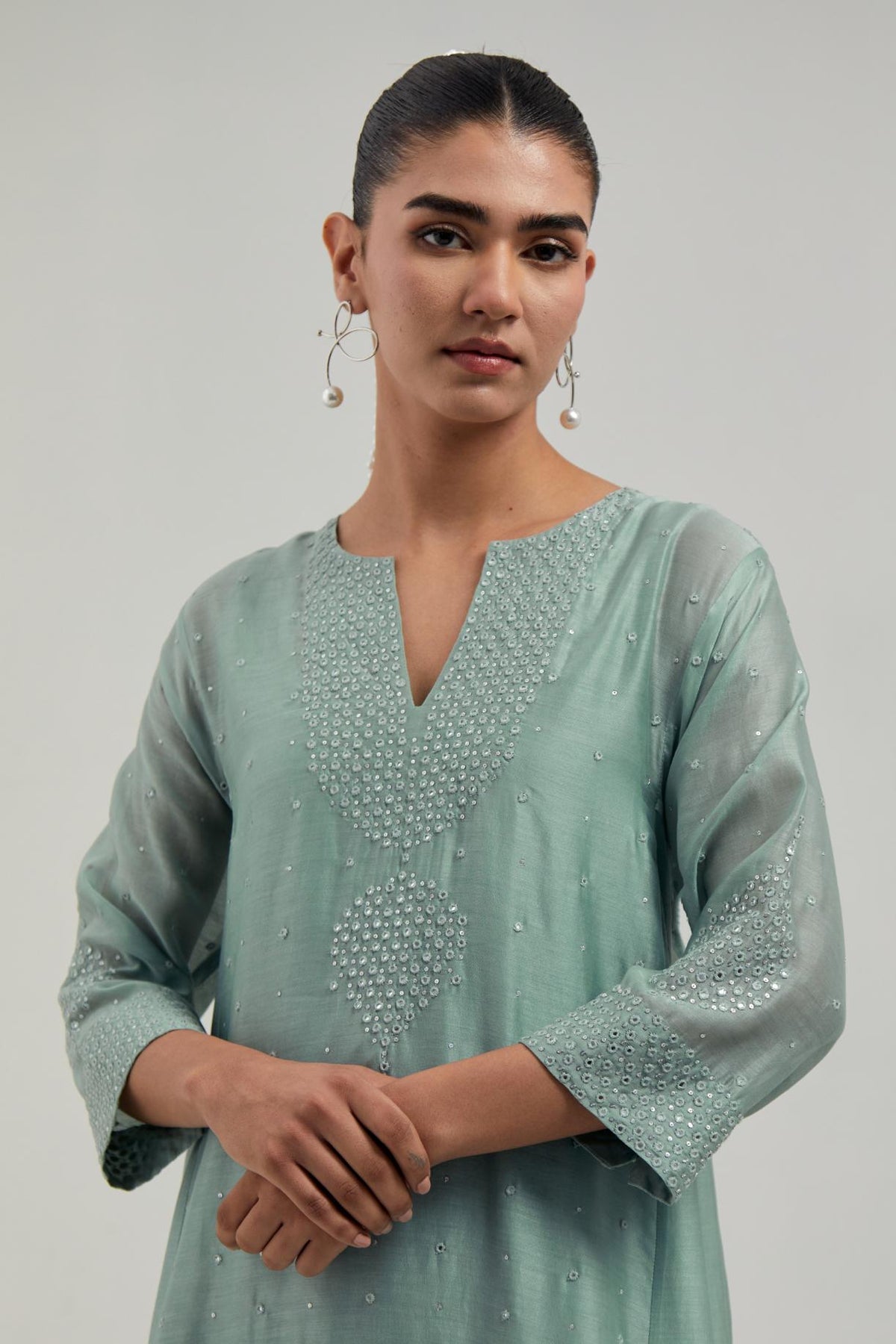 Blue silk Chanderi short kalidar kurta set, with hand embroidered mirror at neck, hem and sleeve edges, highlighted with scattered silver sequins and mirror embellishments all-over.