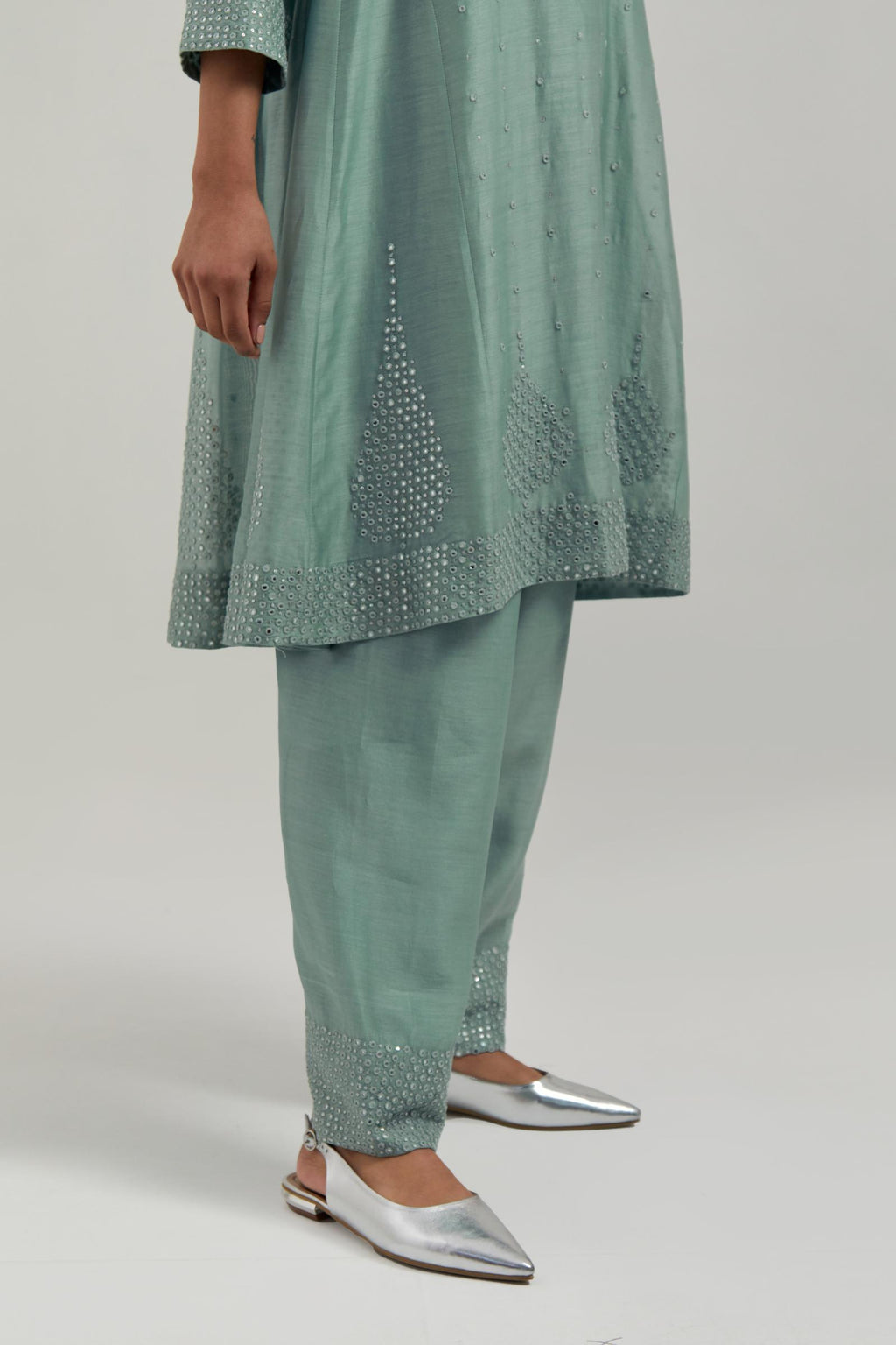 Blue silk Chanderi short kalidar kurta set, with hand embroidered mirror at neck, hem and sleeve edges, highlighted with scattered silver sequins and mirror embellishments all-over.