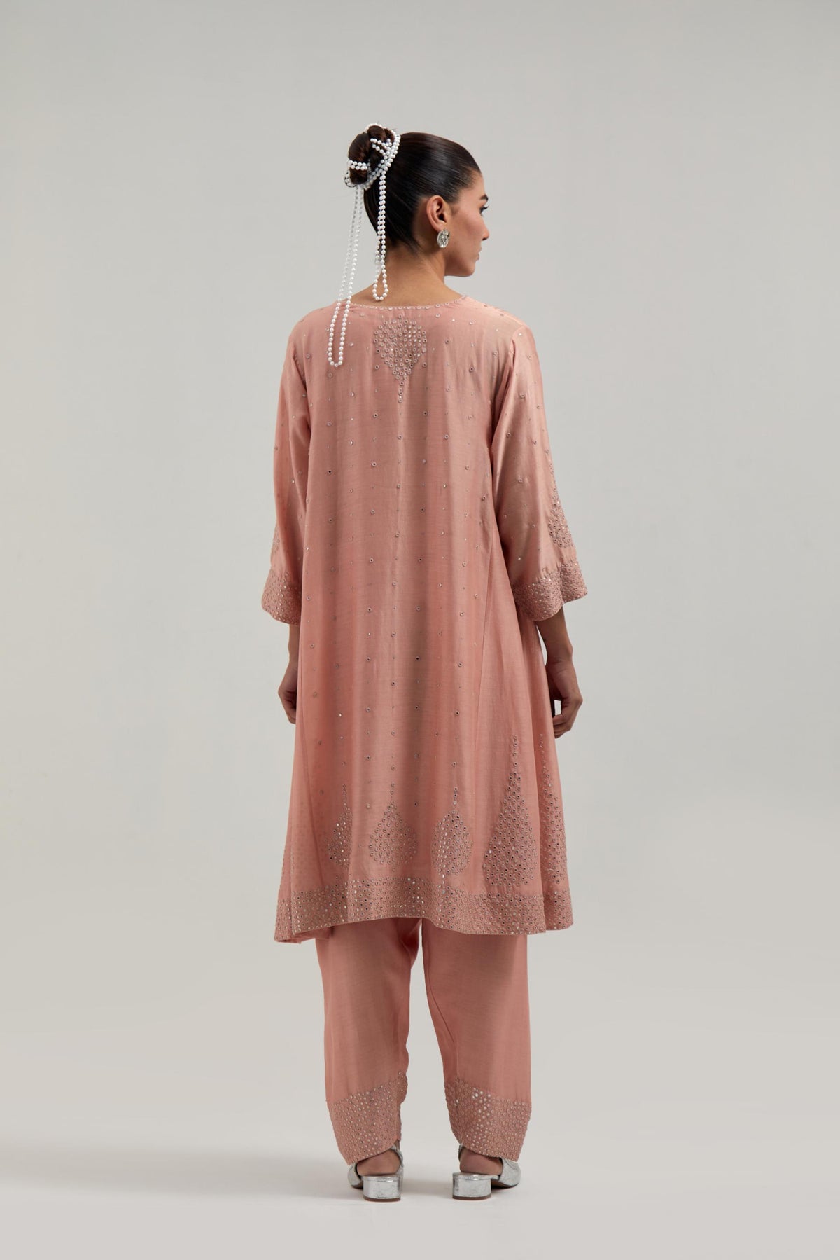 Peach silk Chanderi short kalidar kurta set, with hand embroidered mirror at neck, hem and sleeve edges, highlighted with scattered silver sequins and mirror embellishments all-over.