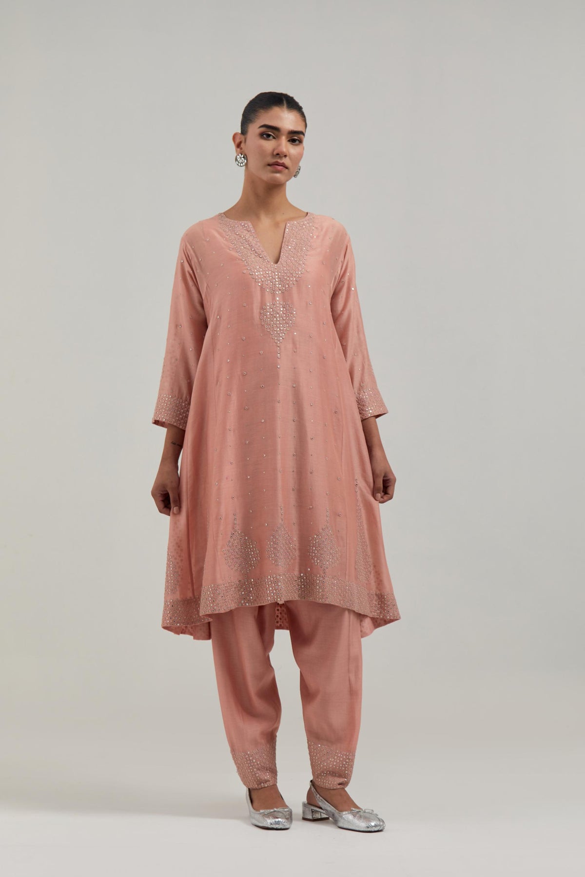 Peach silk Chanderi short kalidar kurta set, with hand embroidered mirror at neck, hem and sleeve edges, highlighted with scattered silver sequins and mirror embellishments all-over.