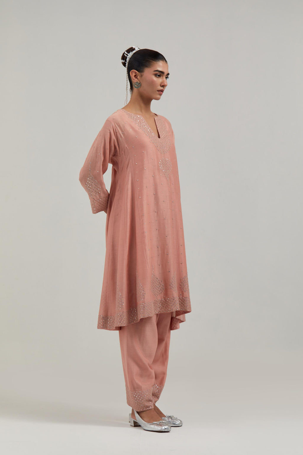 Peach silk Chanderi short kalidar kurta set, with hand embroidered mirror at neck, hem and sleeve edges, highlighted with scattered silver sequins and mirror embellishments all-over.