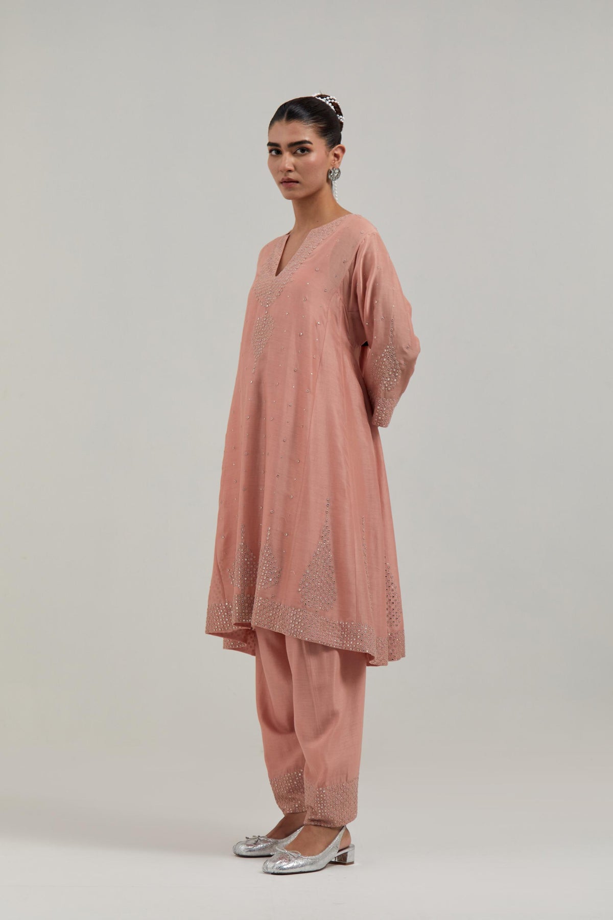 Peach silk Chanderi short kalidar kurta set, with hand embroidered mirror at neck, hem and sleeve edges, highlighted with scattered silver sequins and mirror embellishments all-over.