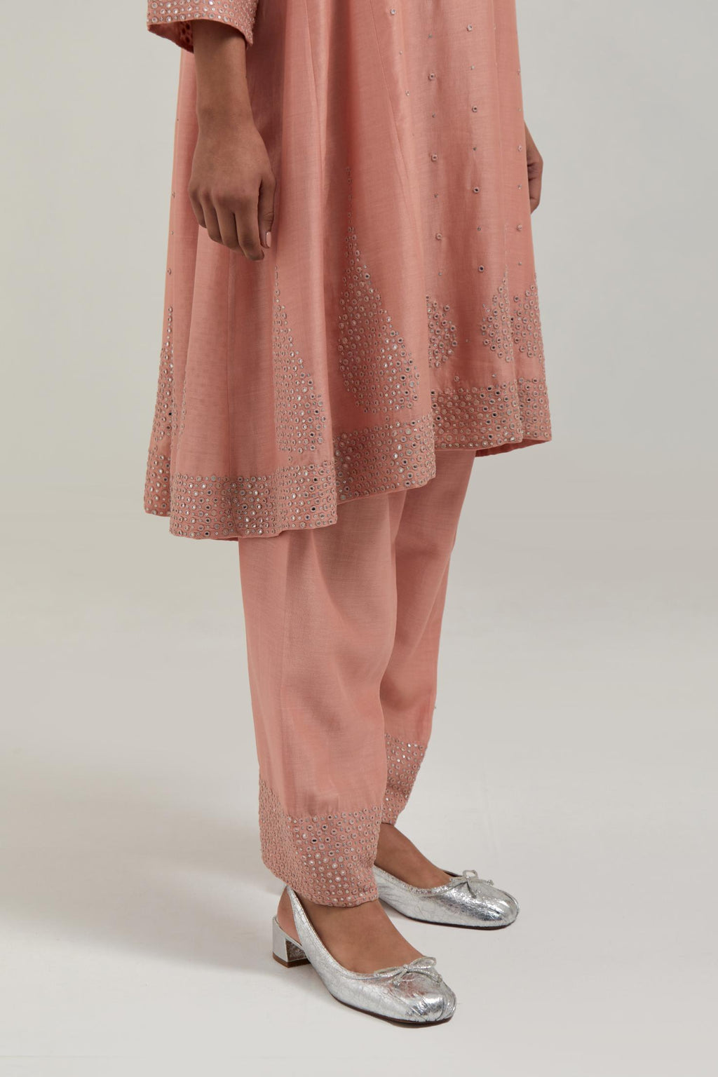 Peach silk Chanderi short kalidar kurta set, with hand embroidered mirror at neck, hem and sleeve edges, highlighted with scattered silver sequins and mirror embellishments all-over.