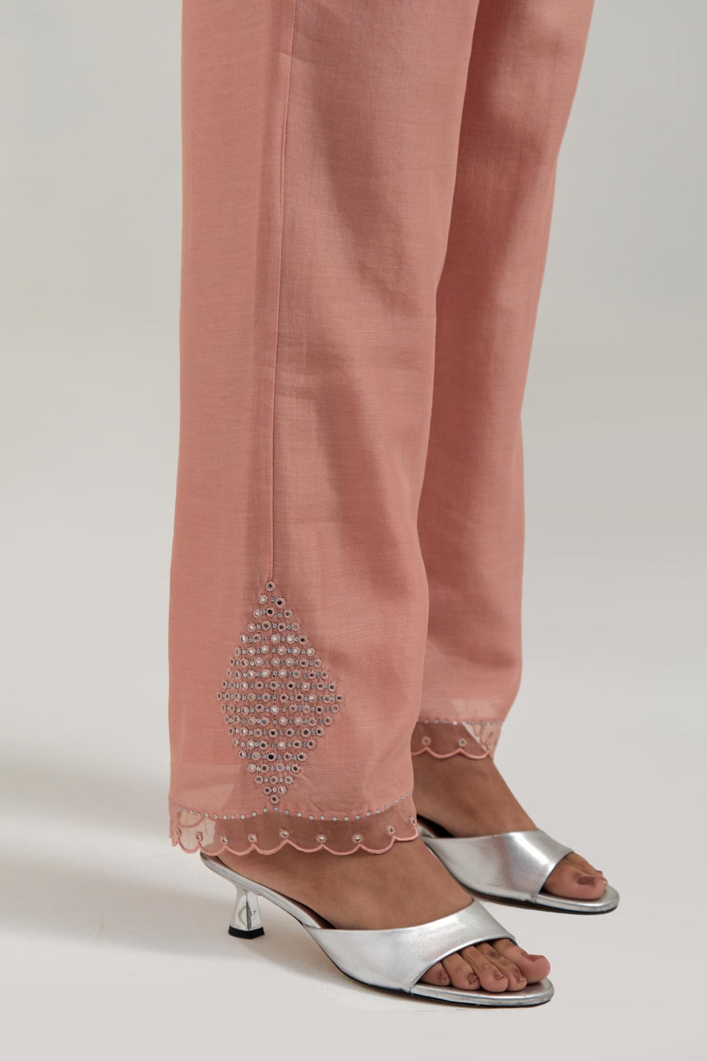 Peach silk Chanderi straight pants with narrow organza scalloped hem and hand-embroidered diamond motifs with delicate mirror & sequins work at the sides.