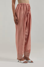 Peach silk Chanderi salwar with hand-embroidered mirror & sequins work in a broad border at the hem.