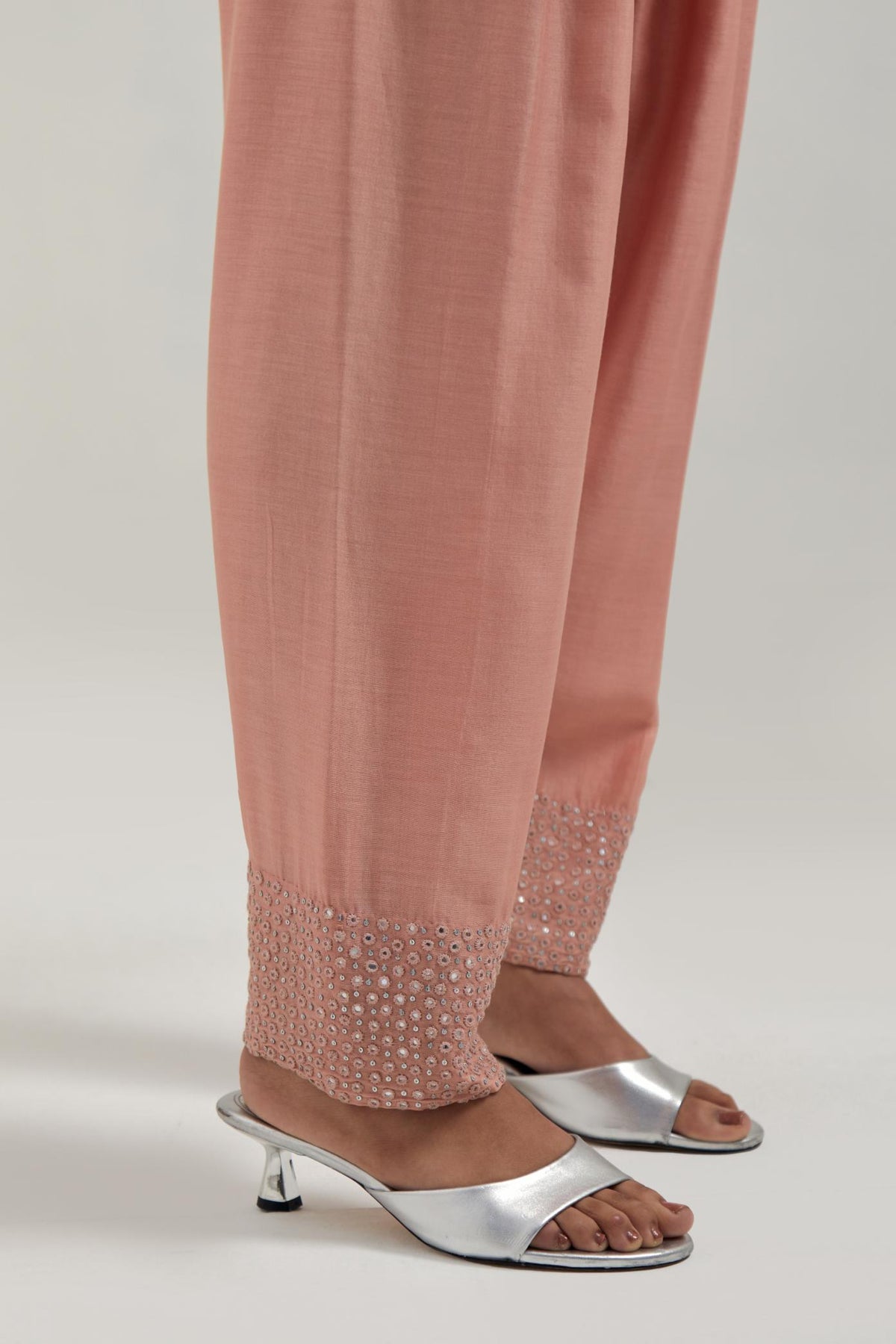 Peach silk Chanderi salwar with hand-embroidered mirror & sequins work in a broad border at the hem.