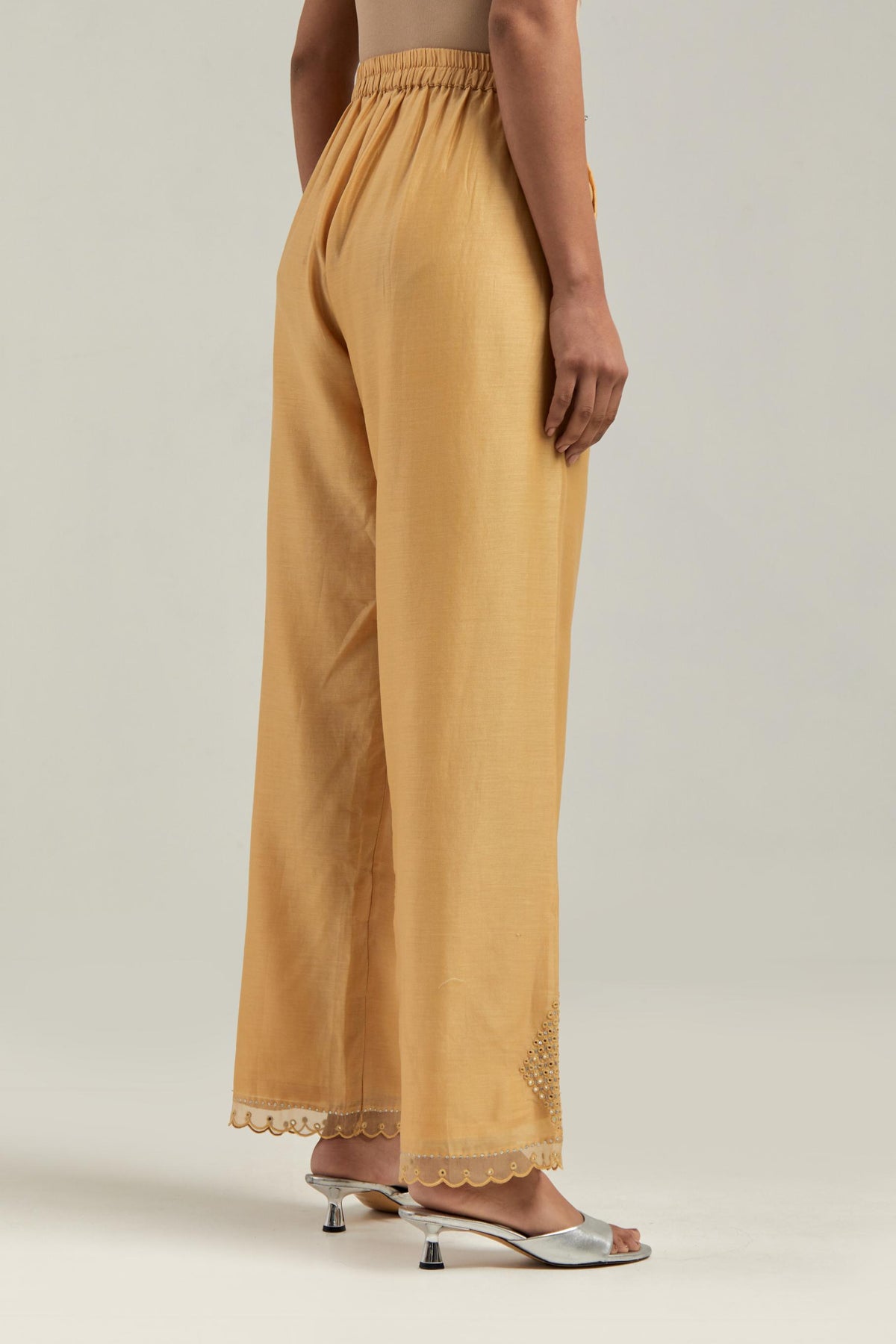 Yellow silk Chanderi straight pants with narrow organza scalloped hem and hand-embroidered diamond motifs with delicate mirror & sequins work at the sides.