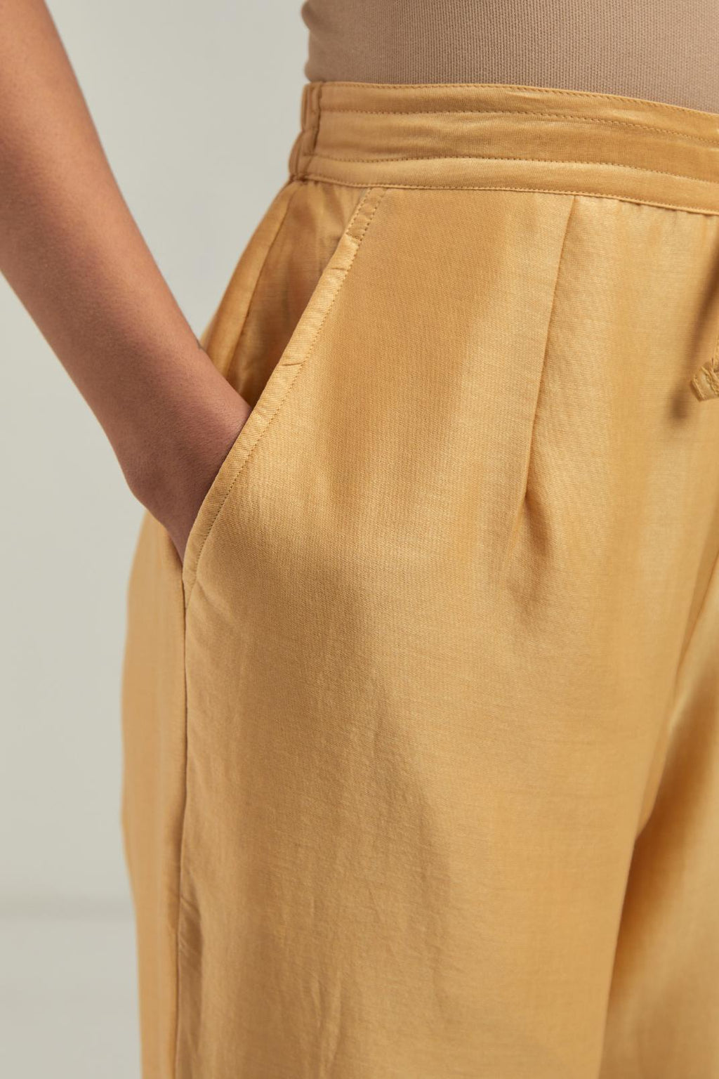 Yellow silk Chanderi pants with hand-embroidered paisley motifs with delicate mirror and sequins work at the hem.