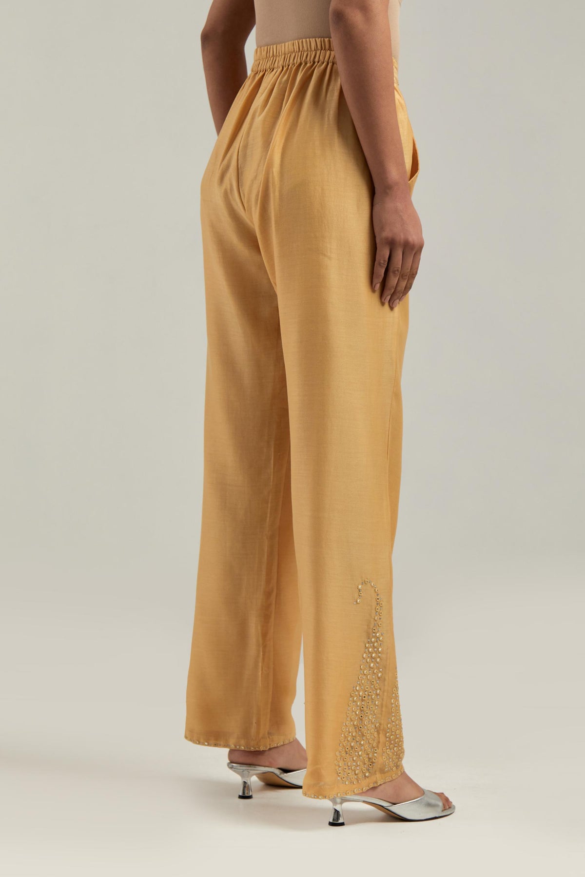 Yellow silk Chanderi pants with hand-embroidered paisley motifs with delicate mirror and sequins work at the hem.