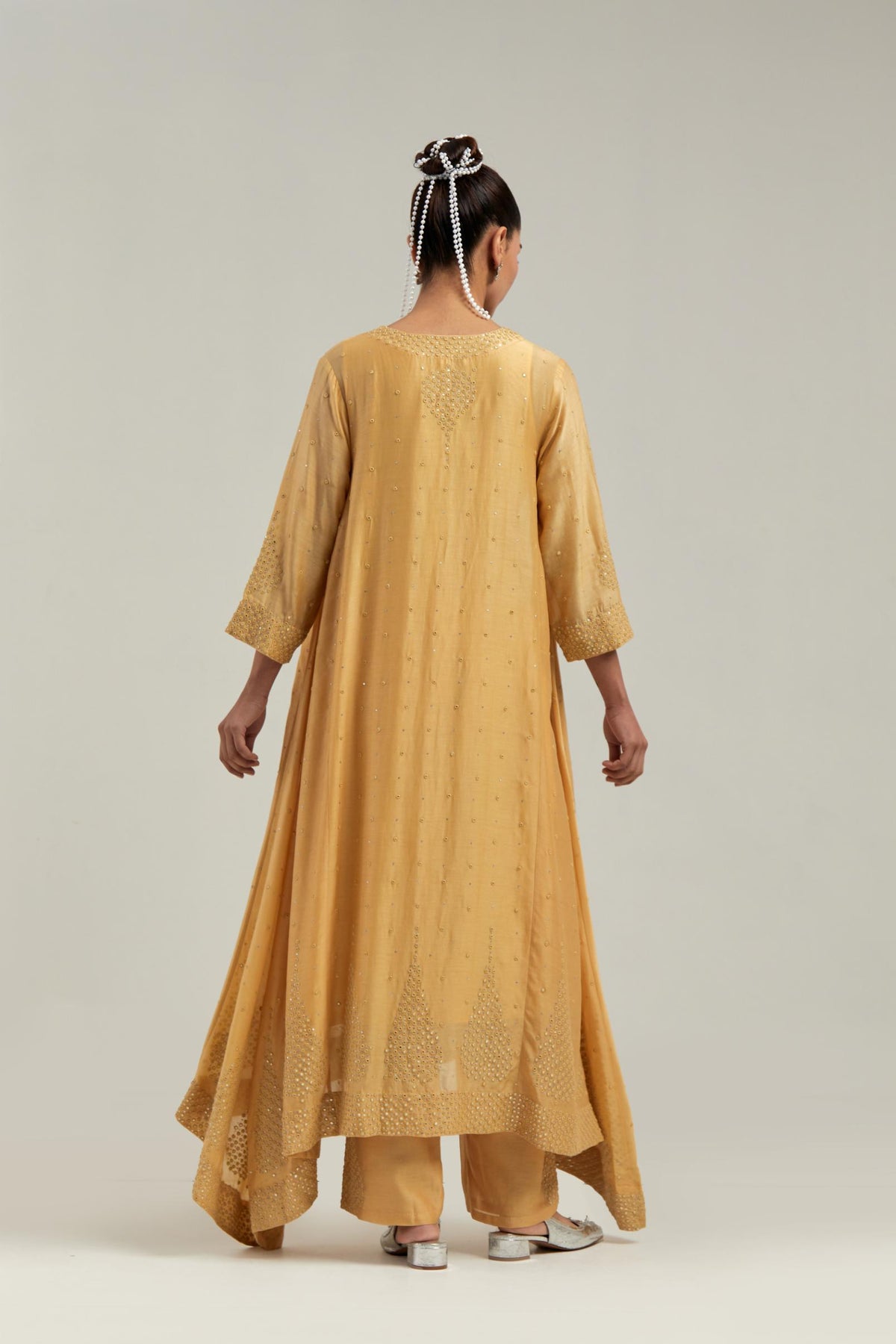 Yellow silk Chanderi kurta set with asymmetric hem and hand-embroidered leaf motifs with delicate mirror and sequins work at the neck, sleeves, and hem, with a mirror border running along the edges.