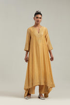Yellow silk Chanderi kurta set with asymmetric hem and hand-embroidered leaf motifs with delicate mirror and sequins work at the neck, sleeves, and hem, with a mirror border running along the edges.