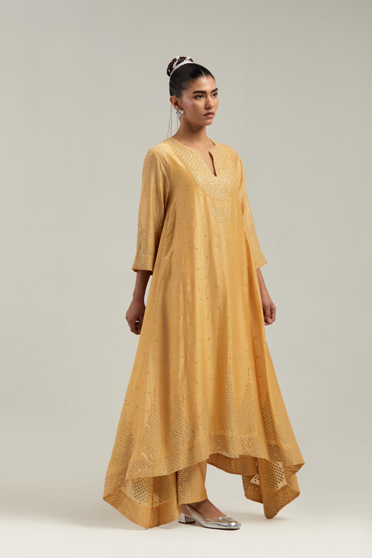 Yellow silk Chanderi kurta set with asymmetric hem and hand-embroidered leaf motifs with delicate mirror and sequins work at the neck, sleeves, and hem, with a mirror border running along the edges.