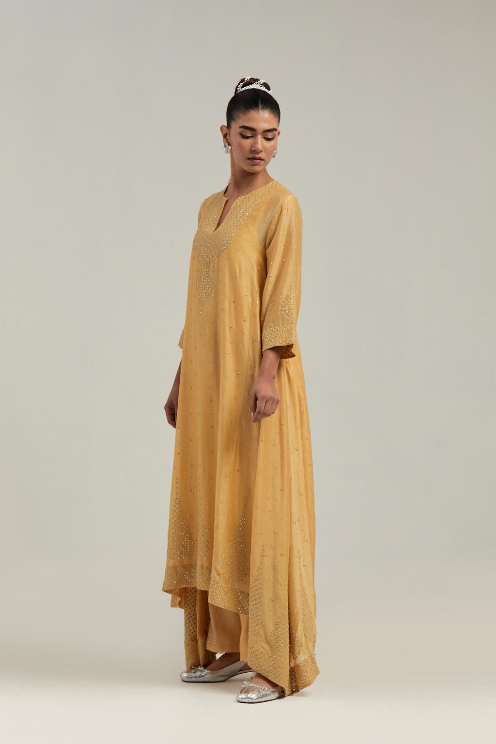 Yellow silk Chanderi kurta set with asymmetric hem and hand-embroidered leaf motifs with delicate mirror and sequins work at the neck, sleeves, and hem, with a mirror border running along the edges.