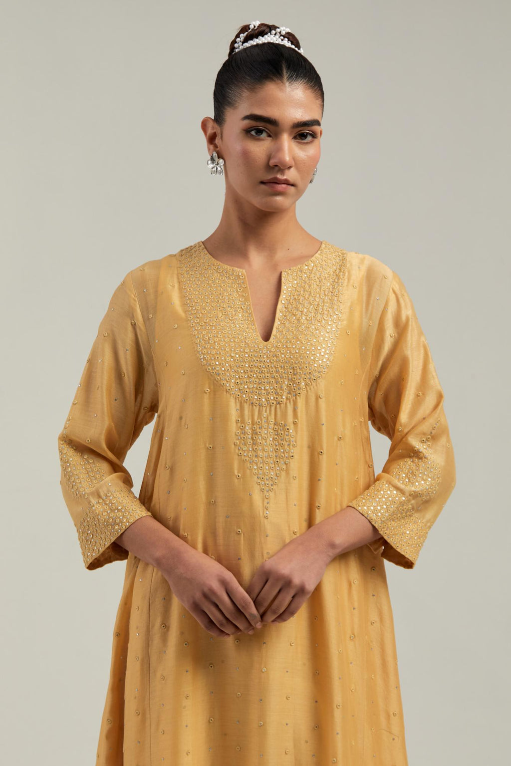Yellow silk Chanderi kurta set with asymmetric hem and hand-embroidered leaf motifs with delicate mirror and sequins work at the neck, sleeves, and hem, with a mirror border running along the edges.