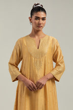 Yellow silk Chanderi kurta set with asymmetric hem and hand-embroidered leaf motifs with delicate mirror and sequins work at the neck, sleeves, and hem, with a mirror border running along the edges.