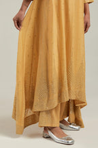 Yellow silk Chanderi kurta set with asymmetric hem and hand-embroidered leaf motifs with delicate mirror and sequins work at the neck, sleeves, and hem, with a mirror border running along the edges.