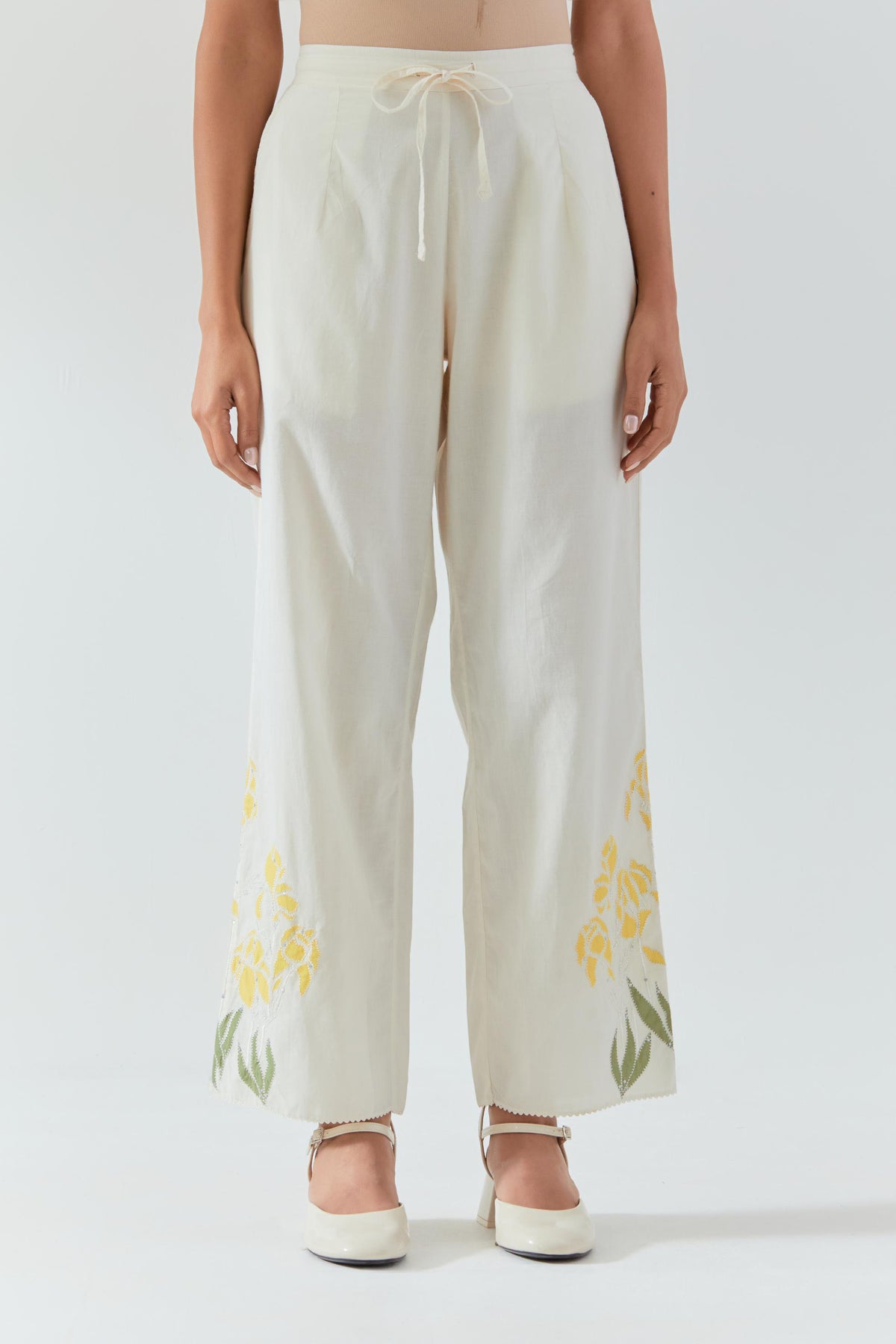 Off white cotton straight pants detailed with yellow & green colored applique, highlighted with bead & sequins work.