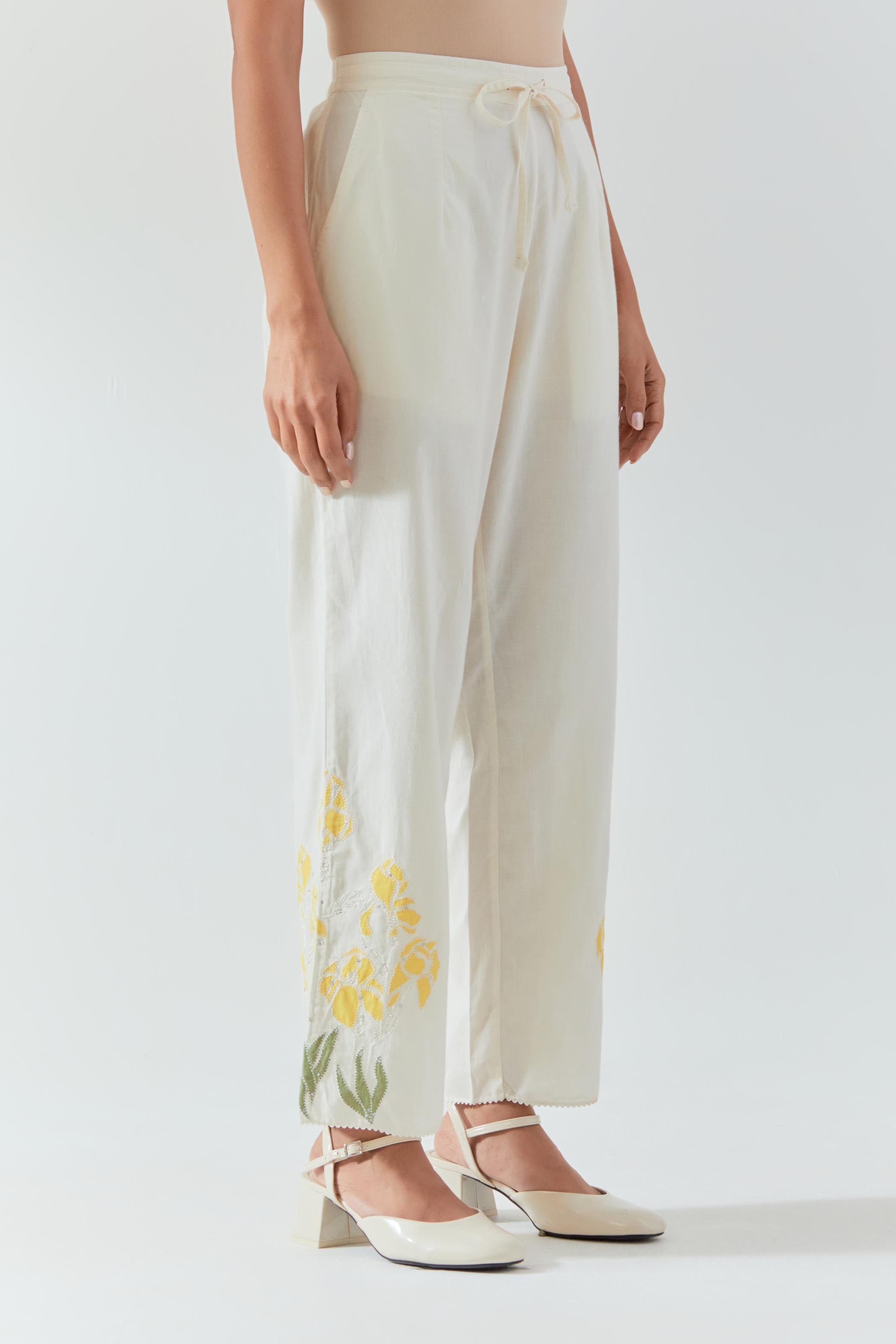 Off white cotton straight pants detailed with yellow & green colored applique, highlighted with bead & sequins work.