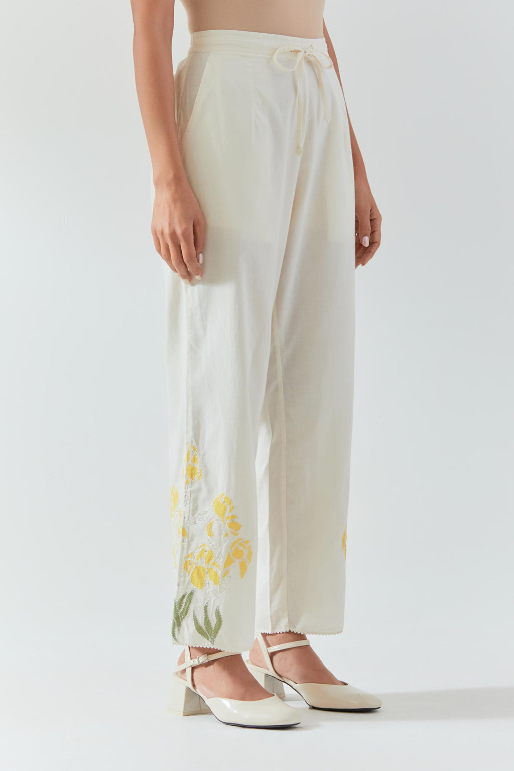 Off white cotton straight pants detailed with yellow & green colored applique, highlighted with bead & sequins work.