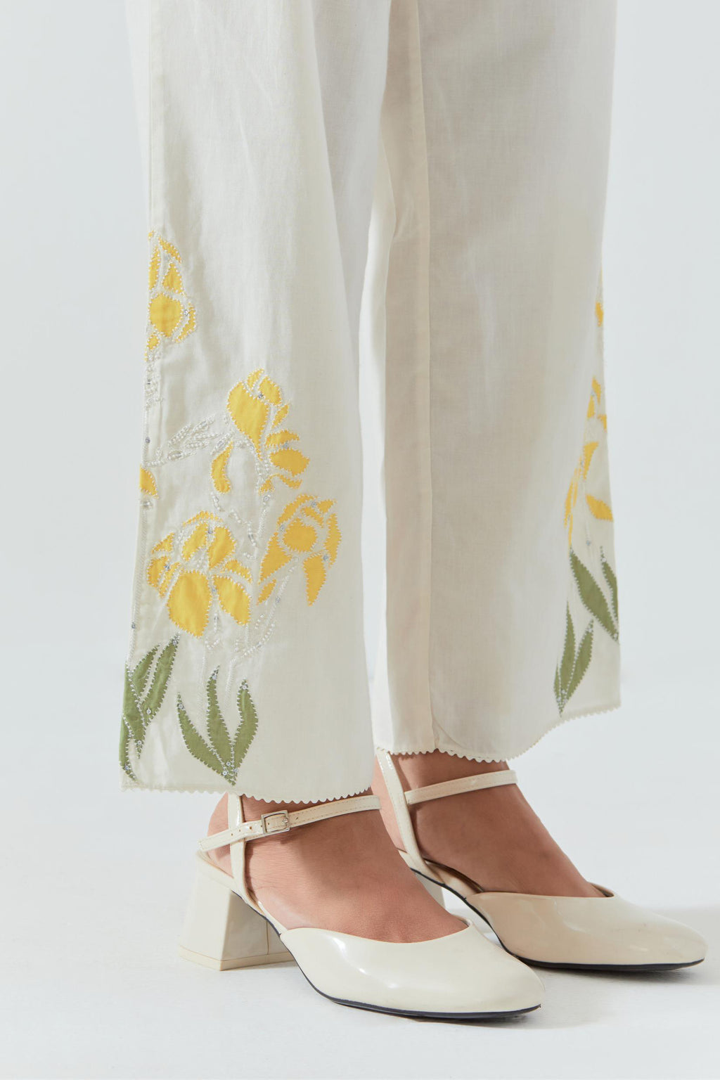 Off white cotton straight pants detailed with yellow & green colored applique, highlighted with bead & sequins work.