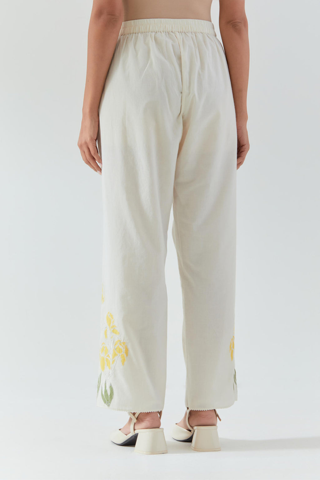 Off white cotton straight pants detailed with yellow & green colored applique, highlighted with bead & sequins work.